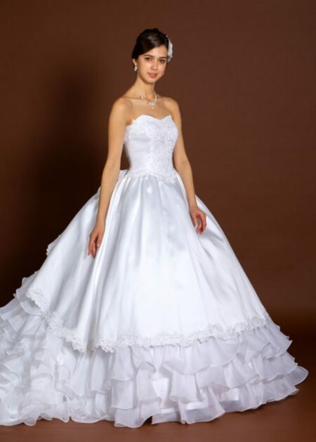 Abito da sposa in raso e organza senza spalline con applicazioni di pizzo e perline nel décolleté.