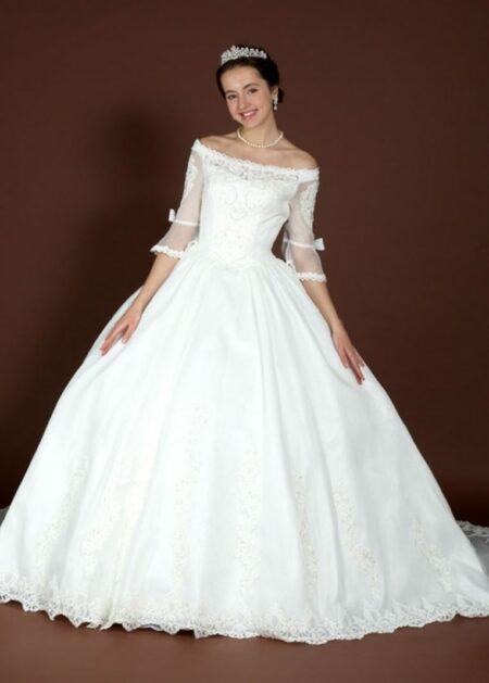 Abito su misura ampio in tulle velato dal pizzo rebrodè ricamato che ricopre il corpino e forma uno scollo a Barca con manica 3/4