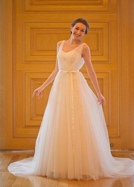 Abito da sposa stile impero realizzato in raso e tulle con scollo a cuore e spalline trasparenti. Fascia in vita che chiude con un fiocco e gonna morbida