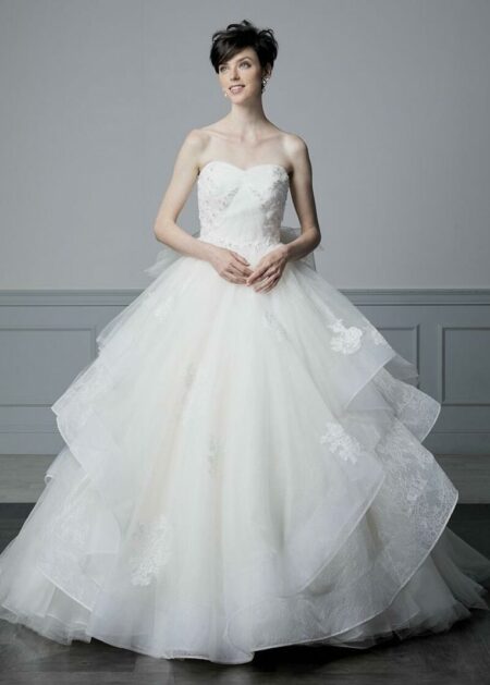 Abito da sposa stile principessa con bustino semirigido adornato da applicazioni in pizzo e decorato con paillettes, strass e perline gonna ampia in tulle con volants