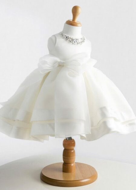Raffinato vestitino bianco da battesimo con fiocco staccabile e decorazioni di pietre scintillanti firmato Sposamore della collezione 2021