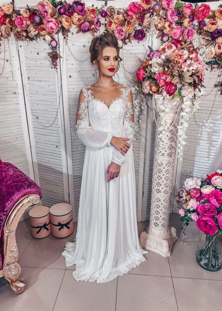 Un vestito da sposa in soffice chiffon plissettato, questo abito da sposa è arricchito da maniche lunghe semitrasparenti