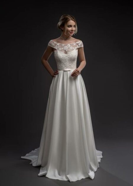 Elegante e sartoriale abito da sposa dallo stile inconfondibile in raso e pizzo con scollatura a barchetta e lunghe file di bottoncini sul dietro